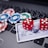 A set of red dice and poker chips are placed on top of a credit card, which is situated on a laptop keyboard. The poker chips are in various colors, including blue, green, red, and white.