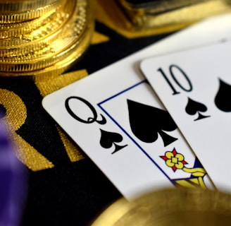 A close-up view of playing cards, specifically a Queen and a Ten of spades, surrounded by shiny gold coins and part of a poker chip, suggesting a gambling or casino theme.