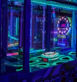 A brightly lit arcade game machine featuring neon lights and colorful graphics. The display shows point values and bonus levels, with vibrant colors reflecting off the glass and surrounding surfaces.